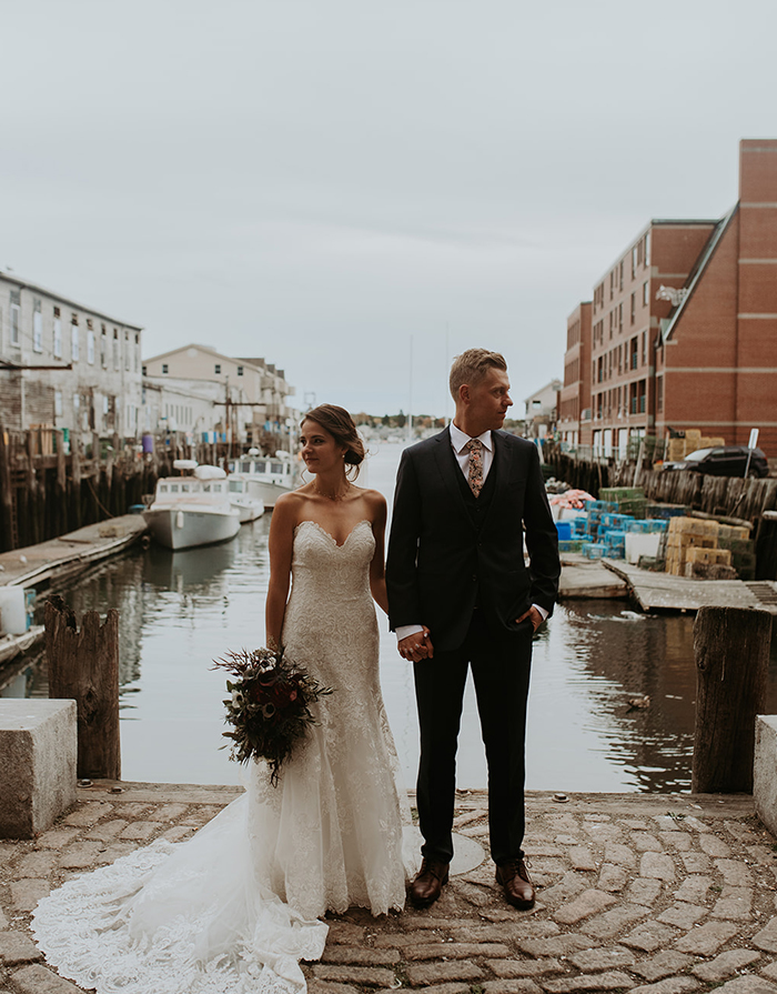 wedding couple holding hands standing near dock